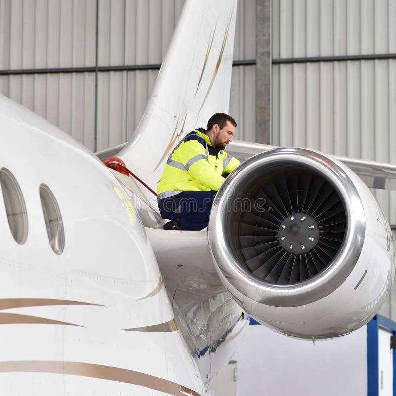 Flughafenarbeitskräfte überprüfen ein Flugzeug auf Sicherheit in einem Hangar stockfotografie Flughafenarbeitskräfte überprüfen ein Flugzeug auf Sicherheit in einem Hangar stockfotografie