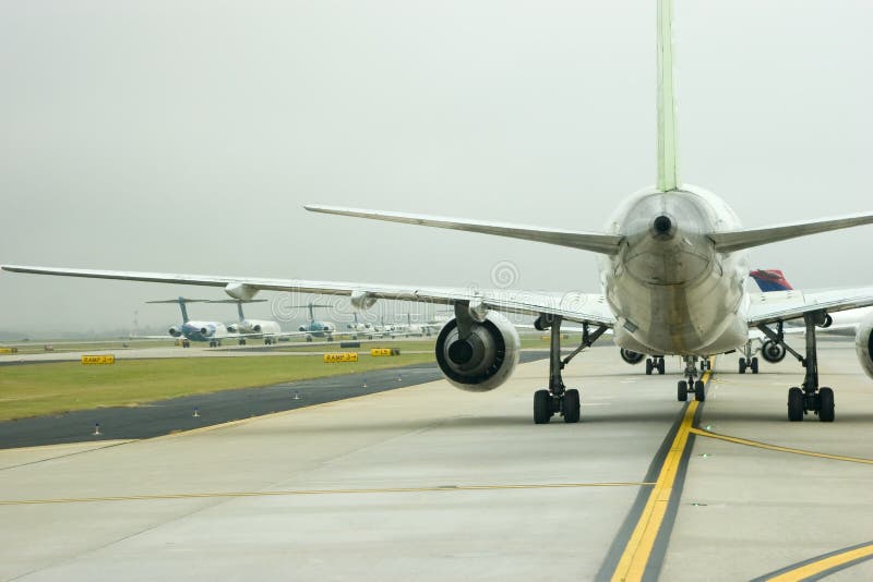 View of airplanes lined up for takeoff under another airplane's wing. View of airplanes lined up for takeoff under another airplane's wing