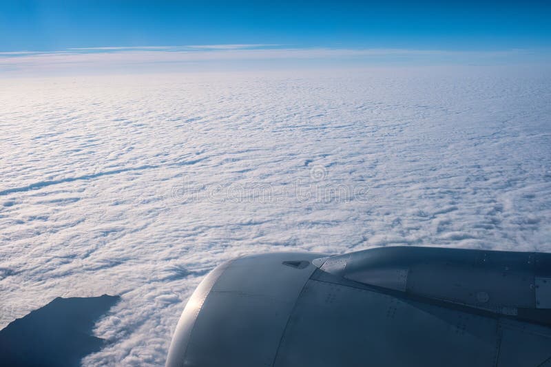 Flugzeugfenster mit Flugzeugmotor über weißen Wolken mit Himmelsansicht. Luftbild aus Flugzeugfenster mit Flugzeugmotor über weißen Wolken mit Panoramaaussicht