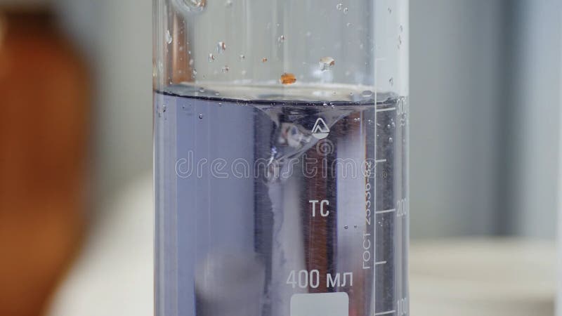Fluid changes color after mixing. Close-up of colorful flask in which the liquid is mixed by a special device stock image