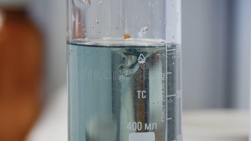 Fluid changes color after mixing. Close-up of colorful flask in which the liquid is mixed by a special device stock image
