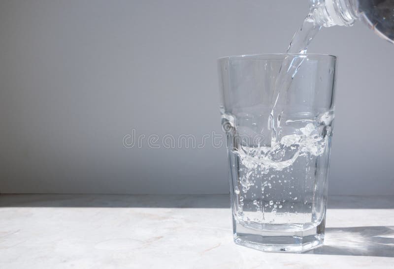 Flujo de agua limpia que fluye de una botella a un vaso con un chorro imagen de archivo libre de regalías Flujo de agua limpia que fluye de una botella a un vaso con un chorro imagen de archivo libre de regalías