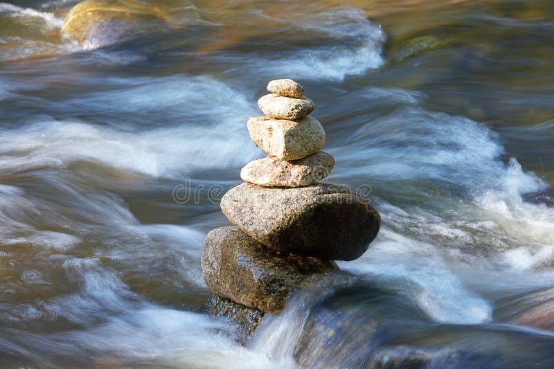 Firm as a rock, stone with water moving around it. Water is blurred because of streaming and movement. Firm as a rock, stone with water moving around it. Water is blurred because of streaming and movement.