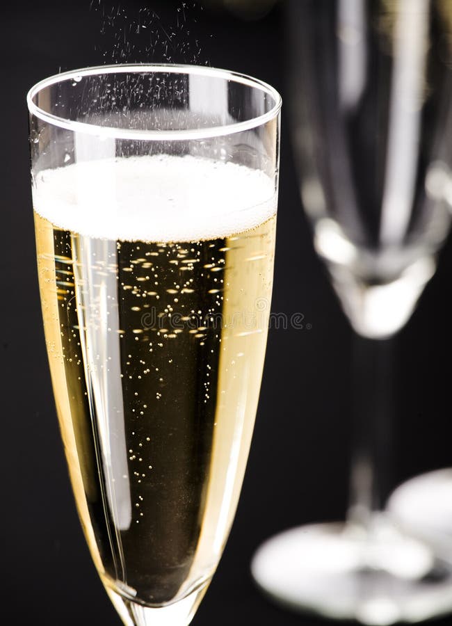 Two Champagne Flutes with Golden Bubbles Make Cheers on Black