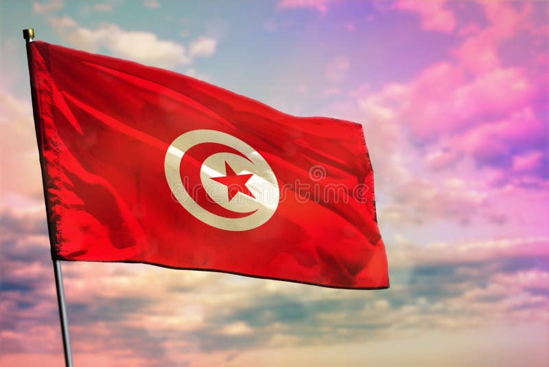 Fluttering Tunisia flag on colorful cloudy sky background. Prosperity concept stock image