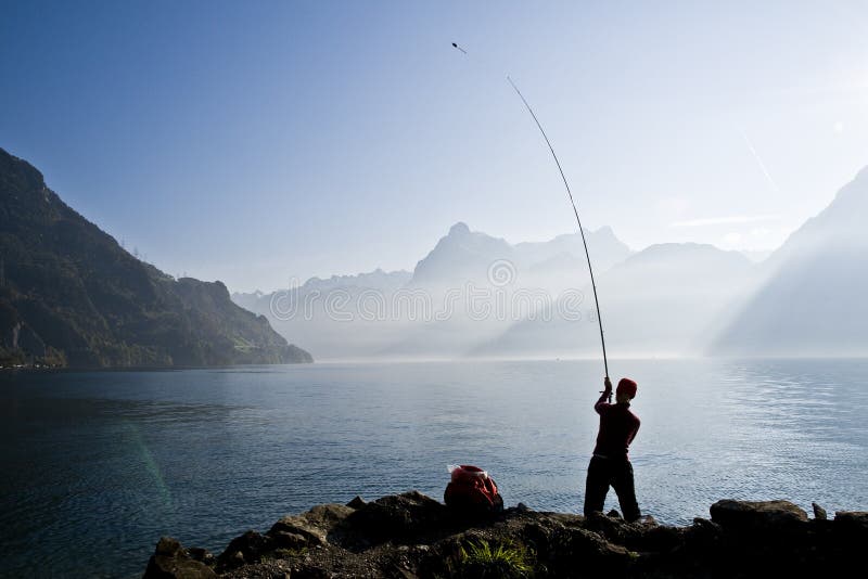 Junge Dame Angeln am Ufer eines Sees in einer malerischen Umgebung von Wasser und die Berge zwischen den Schweizer Alpen.