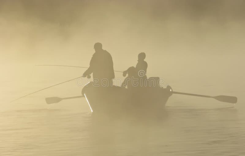 Gente che pesca da una barca deriva nella nebbia mattutina.