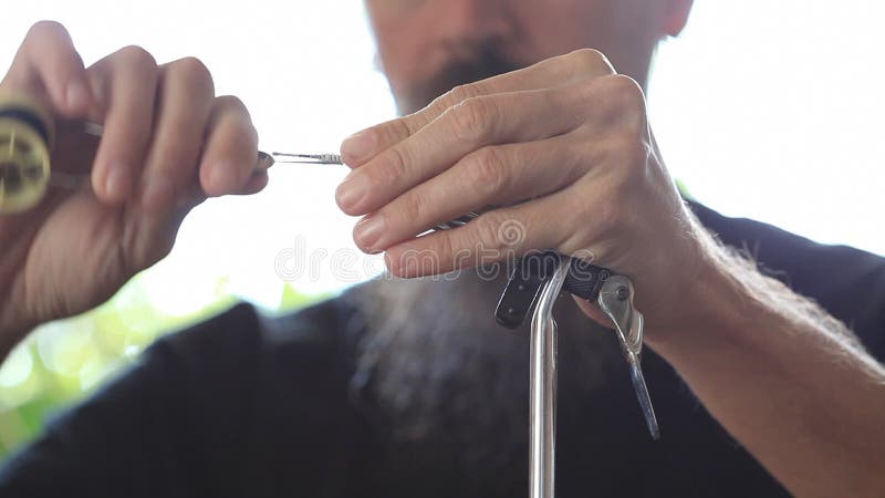 Fly tying - sports fisherman making fishing fly; closeup