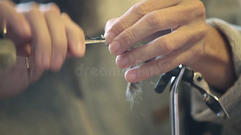 Fly tying - sports fisherman making fishing fly; closeup