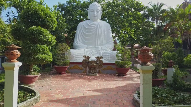 Flycam nadert het witte standbeeld van Boedha onder in tropisch park