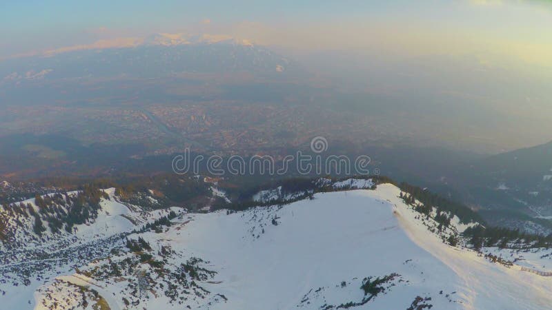Flyg- panorama av storstaden på bergbotten i österrikiska fjällängar, högt snöig maximum