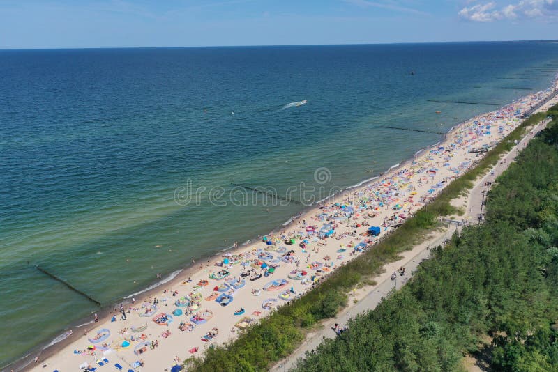 Flyg- perspektivsikt för surr på den soliga stranden med sunbathers med vindskydd och handdukar på havet i touristic stad royaltyfri foto Flyg- perspektivsikt för surr på den soliga stranden med sunbathers med vindskydd och handdukar på havet i touristic stad royaltyfri foto