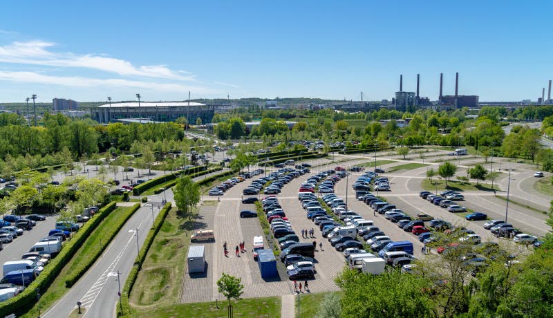 Flyg- sikt över en stor parkeringsplats med många parkerade bilar på en fotbollsarena och den Volkswagen fabriken arkivfoto Flyg- sikt över en stor parkeringsplats med många parkerade bilar på en fotbollsarena och den Volkswagen fabriken arkivfoto