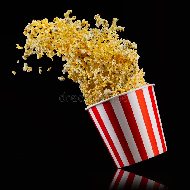 Flyga popcorn från den randiga hinken som isoleras på svart bakgrund royaltyfri foto Flyga popcorn från den randiga hinken som isoleras på svart bakgrund royaltyfri foto