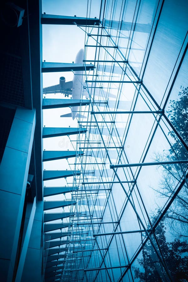 Flygplan ovanför den glass byggnaden arkivbild Flygplan ovanför den glass byggnaden arkivbild
