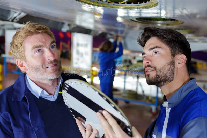 Flygplanservicelag som reparerar nivån i hangar royaltyfri bild Flygplanservicelag som reparerar nivån i hangar royaltyfri bild