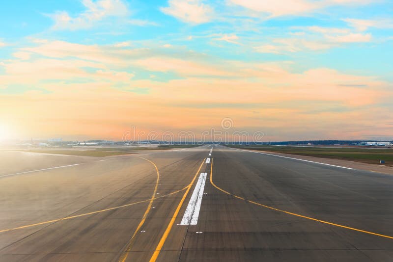 Flygplatslandningsbana efter solnedgånghorisont och pittoreska cirrusmolnmoln i himlen