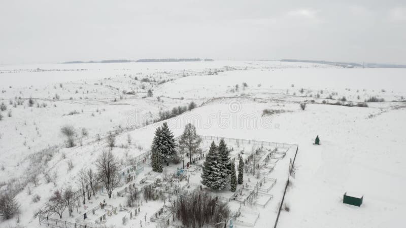 Flygvideo, som flyger över en snösopad landsbygdskyrkogård vid ravinens kant