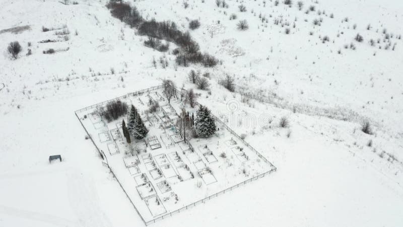 Flygvideo, som flyger över en snösopad landsbygdskyrkogård vid ravinens kant