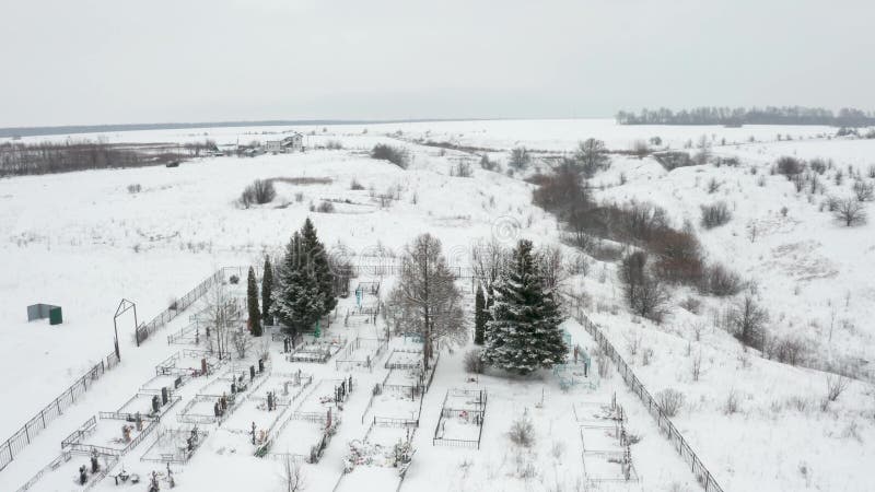 Flygvideo, som flyger över en snösopad landsbygdskyrkogård vid ravinens kant