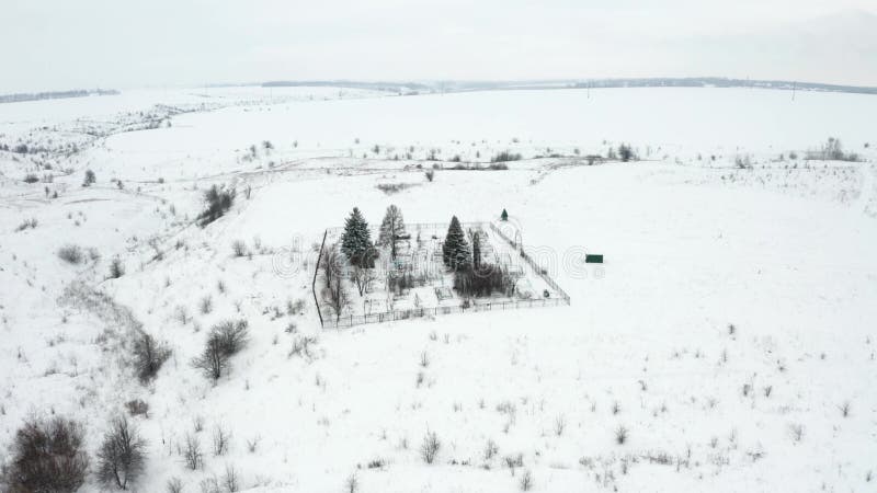 Flygvideo, som flyger över en snösopad landsbygdskyrkogård vid ravinens kant