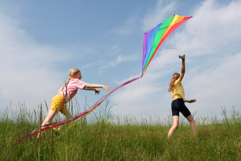 I bambini che volano arcobaleno aquilone nel prato azzurro del cielo di sfondo.