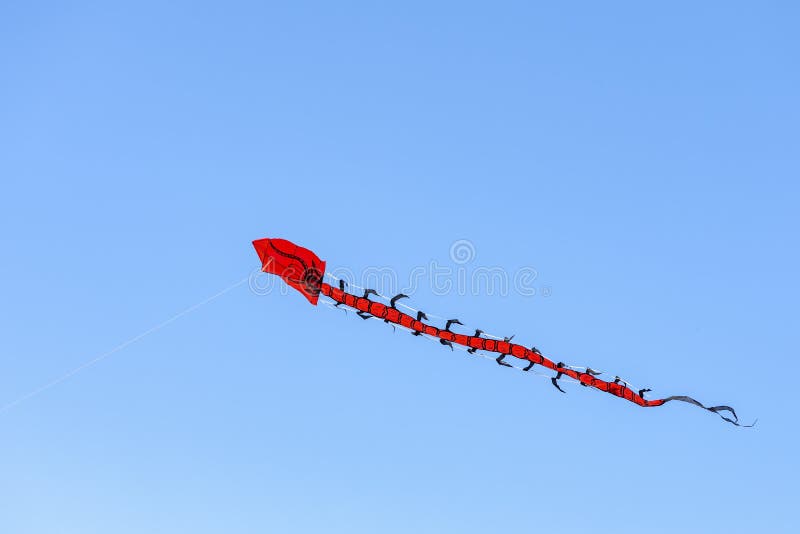 Flying kite. Colorful kite flying in the wind in the blue sky among the clouds. Long serpent in the form of a red dragon stock photos