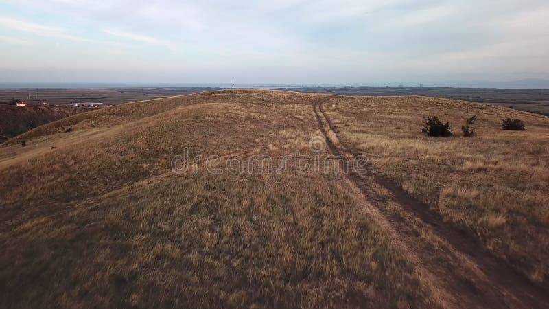 Flying over country road through dry land and hills