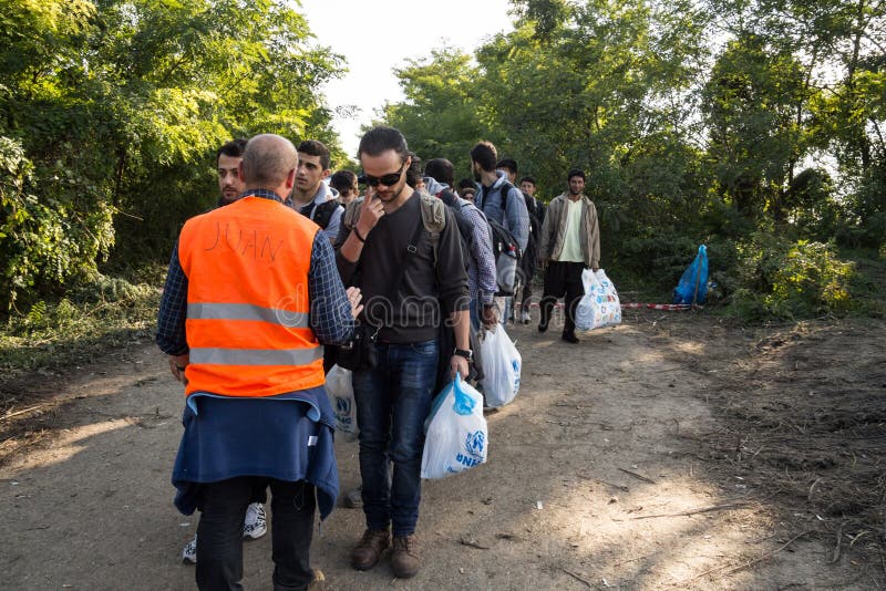Flyktingar som går bärande tunga påsar på Kroatien Serbien, gränsar, mellan städerna av Bapska och Berkasovo på den Balkans rutte