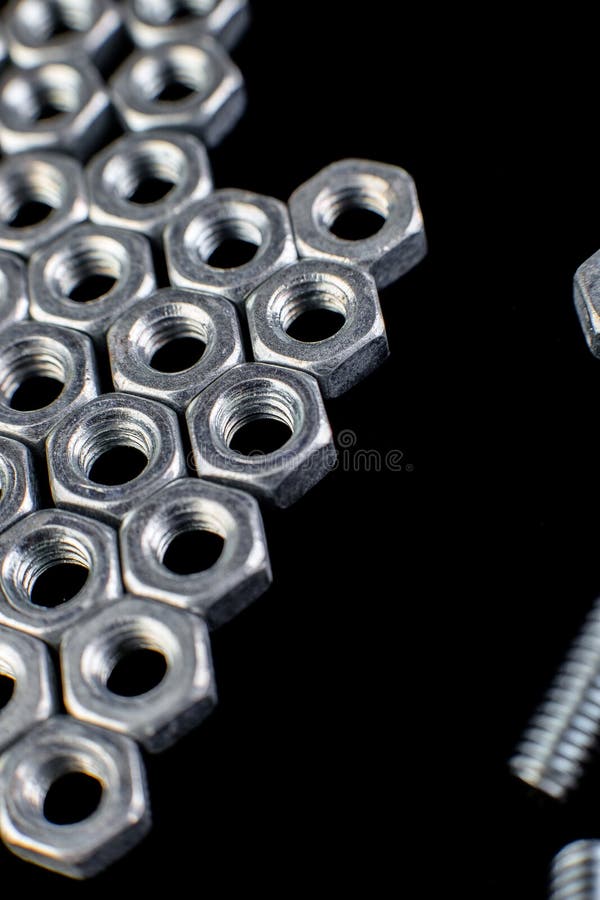Flèche des écrous en métal, boulons sur le fond noir Configuration plate Macro image libre de droits Flèche des écrous en métal, boulons sur le fond noir Configuration plate Macro image libre de droits