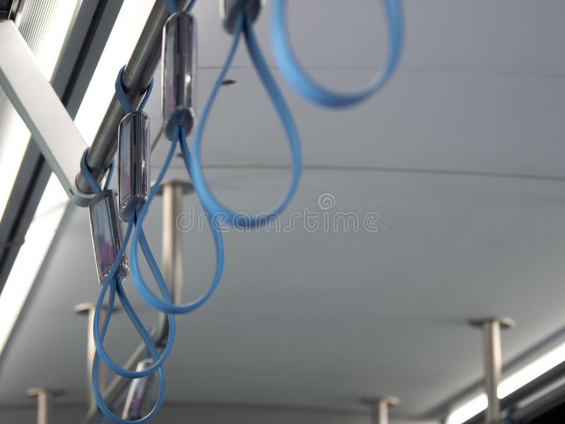 Foco selectivo del metro interior del metro de las manijas azules del lazo para la seguridad del pasajero derecho mientras que us imagen de archivo libre de regalías Foco selectivo del metro interior del metro de las manijas azules del lazo para la seguridad del pasajero derecho mientras que us imagen de archivo libre de regalías
