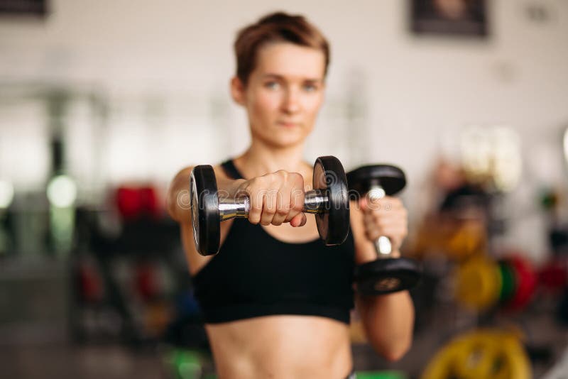 Foco seletivo da mulher desportiva com pesos do peso no gym imagens de stock Foco seletivo da mulher desportiva com pesos do peso no gym imagens de stock