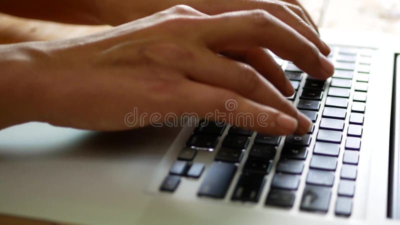 Foco seletivo das mãos de um homem digitando/trabalhando em um teclado de um laptop