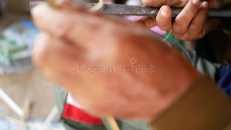 Foco seletivo das mãos de um velho asiático fatiando bambu hábil para preparar materiais para a basquete de bambu