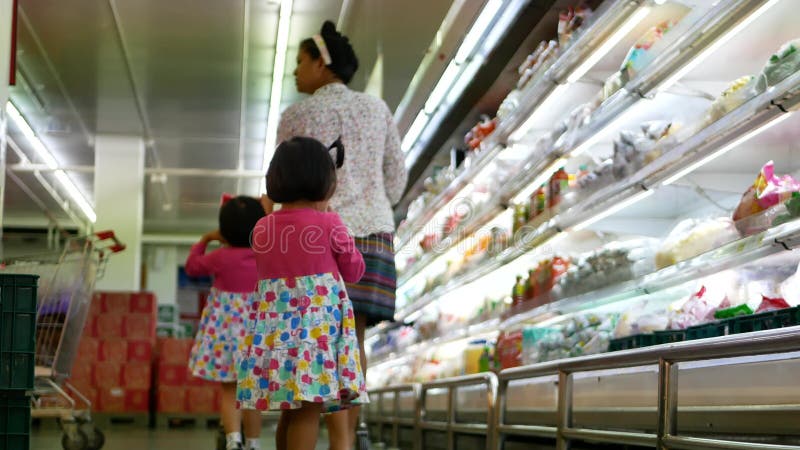 Foco seletivo de meninas, irmãs, seguindo sua mãe para fazer compras em um supermercado