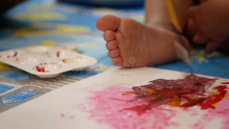 Foco seletivo de um papel branco comum pintado por um pequeno bebê usando um pequeno pincel