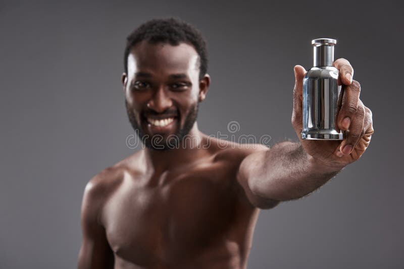 Foco seletivo de um perfume nas mãos de um homem afro-americano alegre foto de stock royalty free Foco seletivo de um perfume nas mãos de um homem afro-americano alegre foto de stock royalty free
