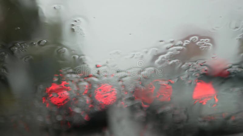 Foco seletivo e diminuição do fundo da chuva no para-brisas inclinado de um carro-piloto num dia chuvoso