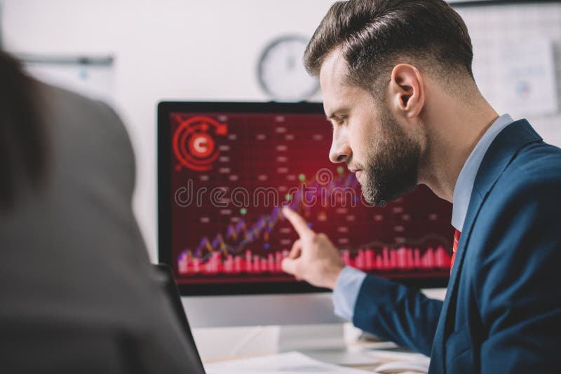 Focus of analyst pointing on charts on computer monitor while working with colleague in office royalty free stock images