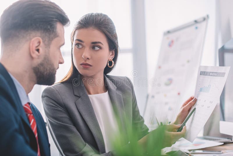 Focus of data analyst pointing on chart to colleague in office royalty free stock photo