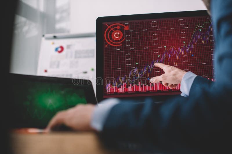 Focus of data analyst pointing with finger at charts on computer monitor at table royalty free stock photography