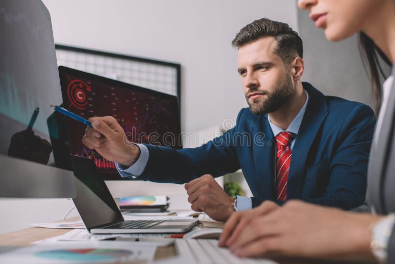 Focus of data analyst pointing on graphs on computer monitor to colleague at table stock photos