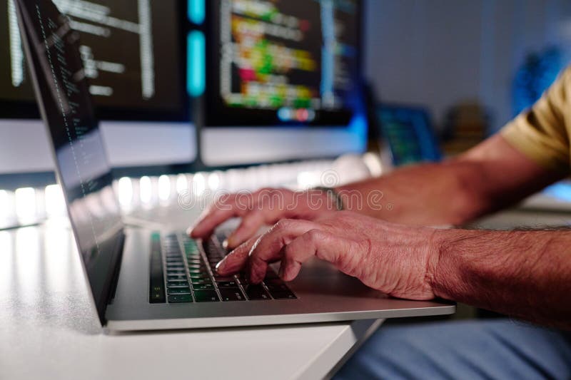Focus on hands of aged male programmer typing on laptop keyboard stock photography