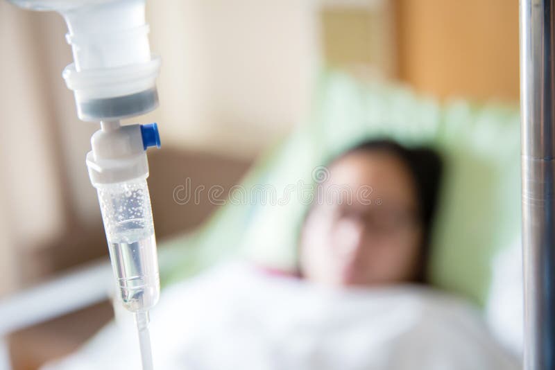 Focus the hanging saline solution with blur patient background.Illness and treatment. Health insurance. Medical Benefits. Reimbursement, Medical expenses. image for illustration, copy space, article.