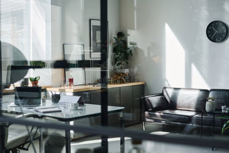 Focus on wall with clock hanging over comfortable black leather couch stock photography