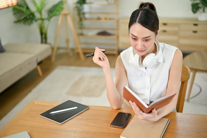 Focused Asian woman making list on a book, thinking and planning new project stock photos