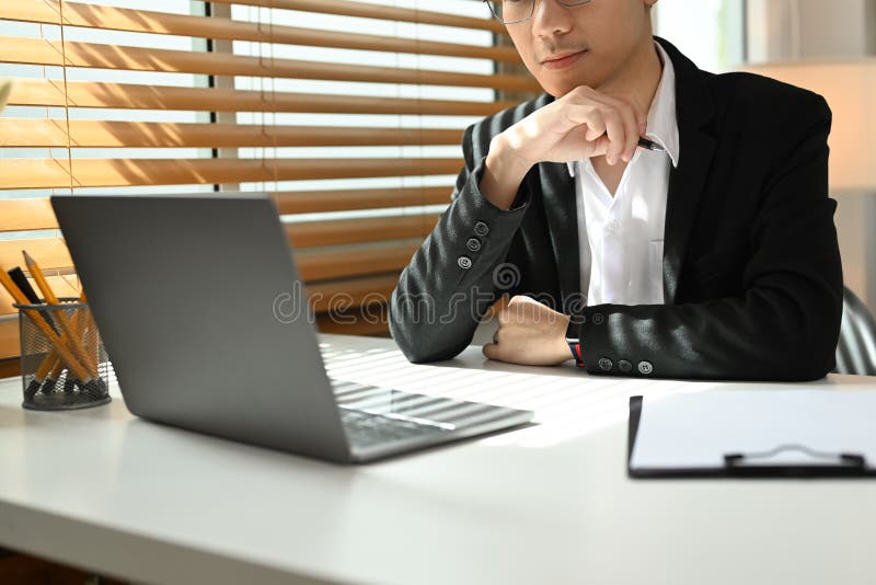 Focused Businessman Analyzing Financial Online Data on Laptop Computer