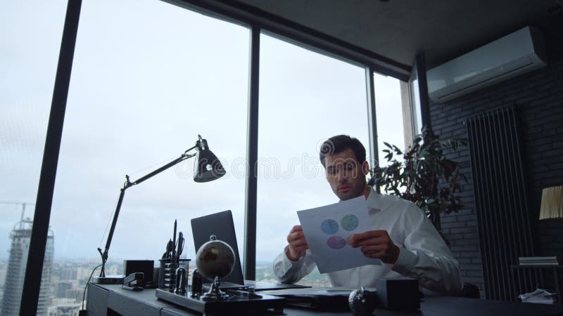 Focused businessman looking at graphics on document in office stock photography