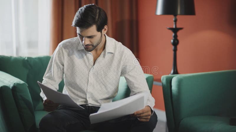 Focused businessman reading documents at hotel. Confident man checking papers royalty free stock photo