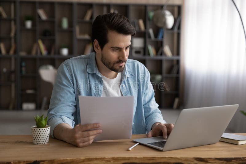 Focused businessman using laptop, working with financial documents, research project royalty free stock photos